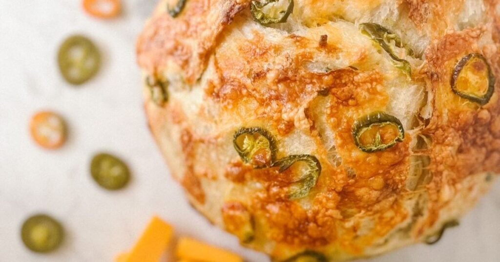 Jalapeno and Cheddar Cheese sourdough add-ins in bread with jalapenos and cheddar cheese next to the loaf.