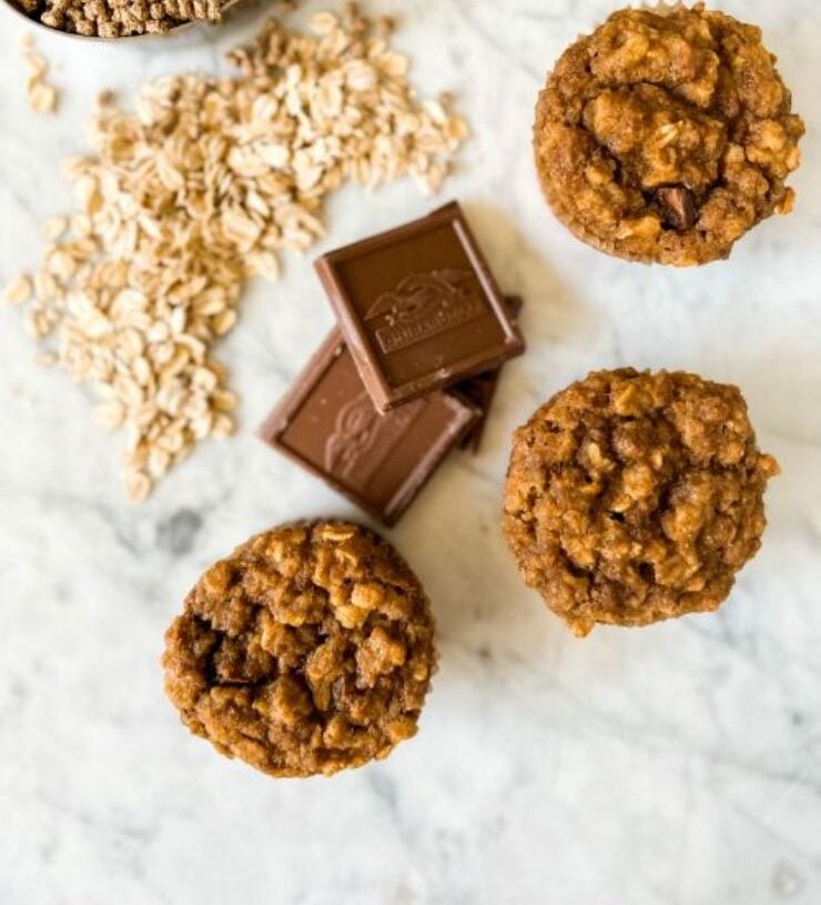 3 sourdough muffins on marble next to chocolate squares, oats, and bran