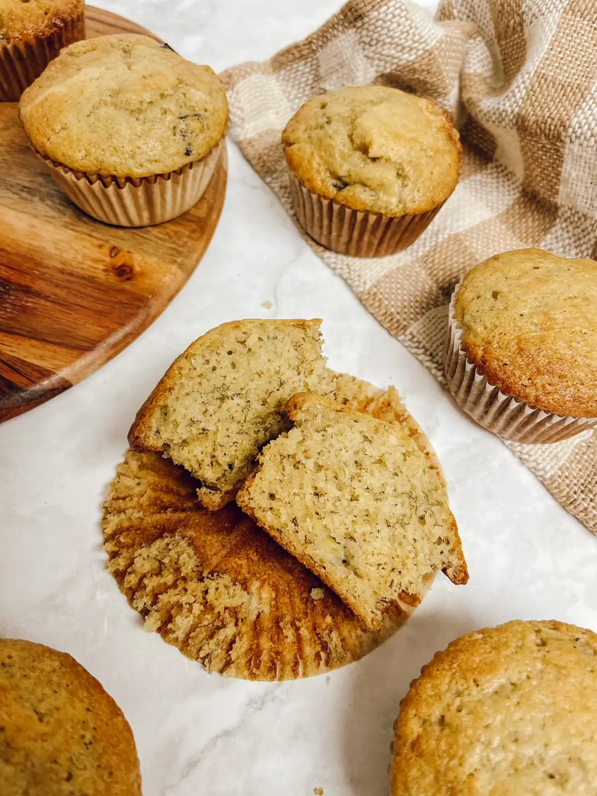 sourdough banana muffins spread out on a board with a tea towel