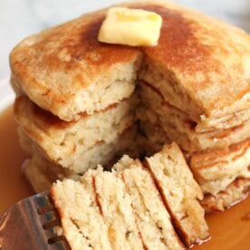 4 Sourdough Discard Pancakes stacked on top of each other with a fork holding a slice of pancake.
