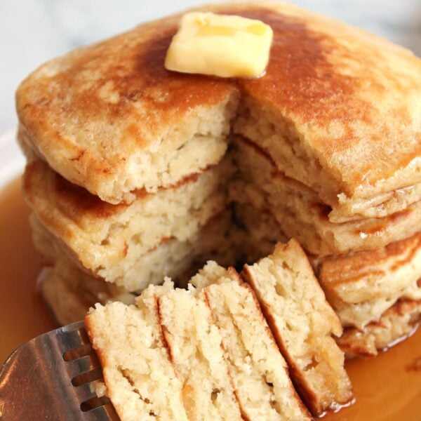 4 Sourdough Discard Pancakes stacked on top of each other with a fork holding a slice of pancake.