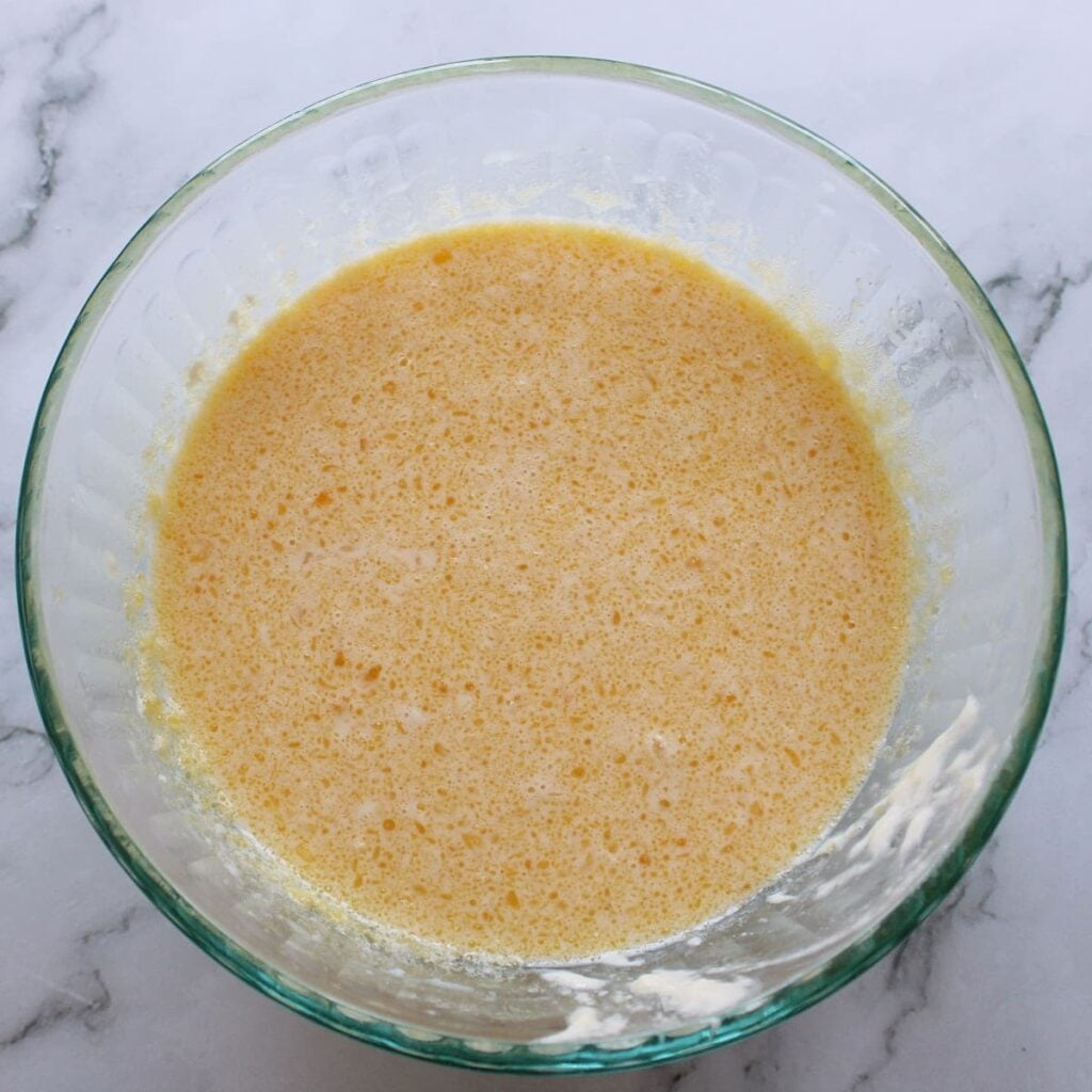 Wet ingredients for Sourdough Discard Pancakes in a clear bowl.