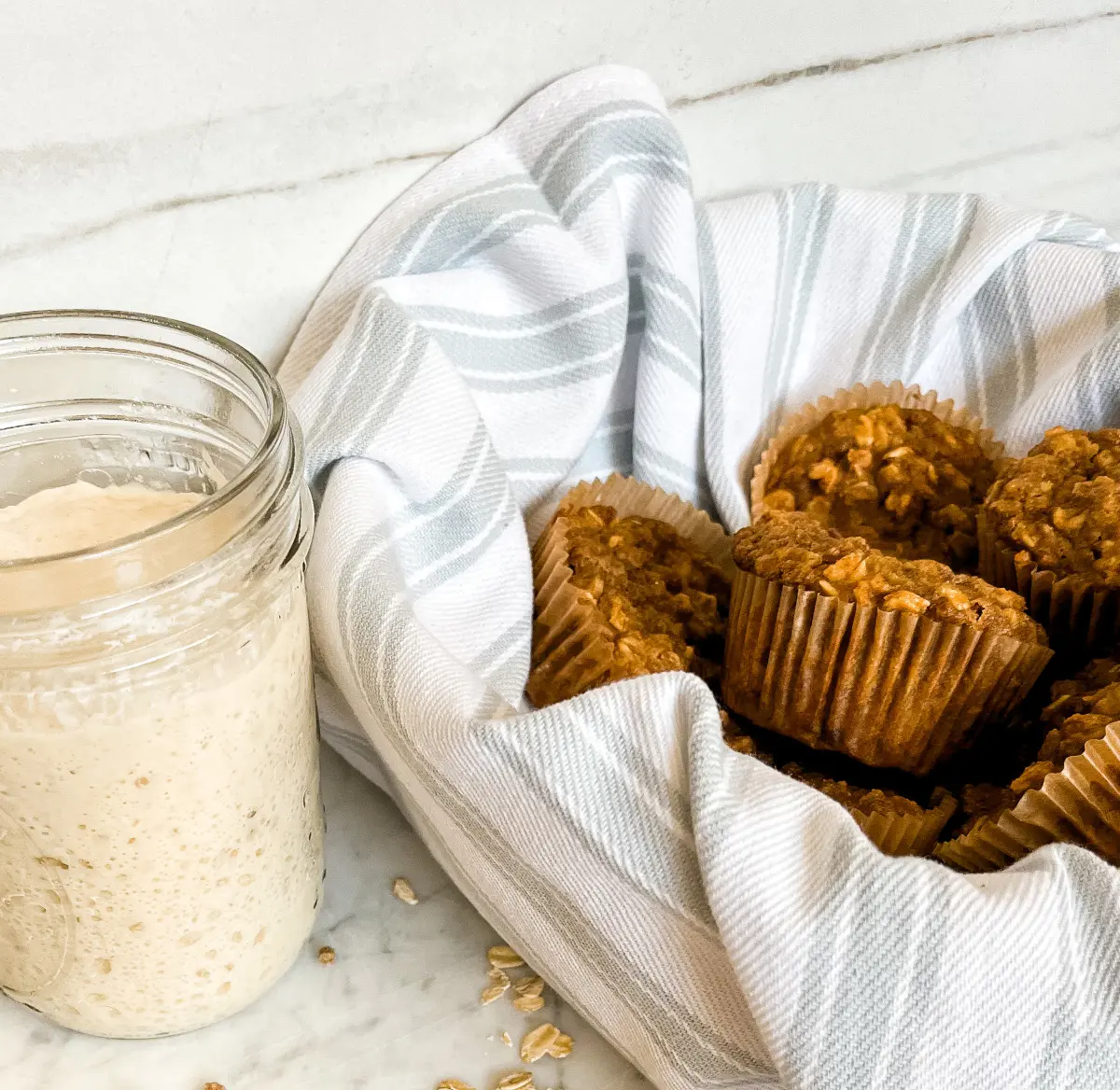 sourdough discard bran muffins in a bowl next to sourdough discard in a jar