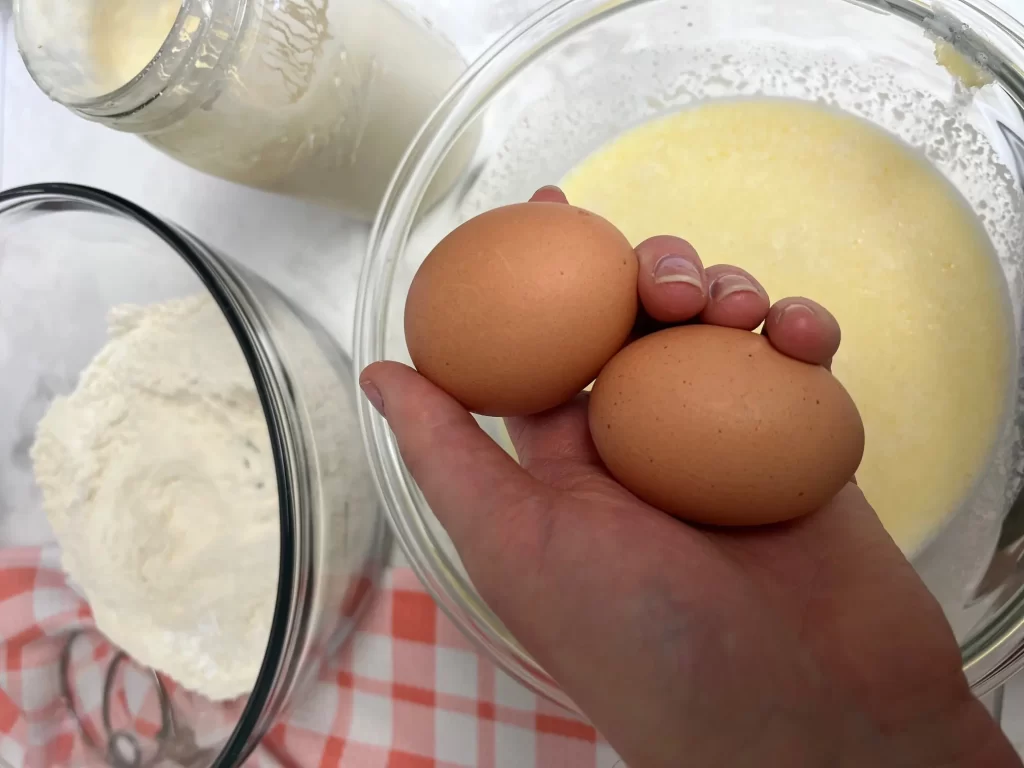 dry and wet ingredients for pancakes with hand holding eggs