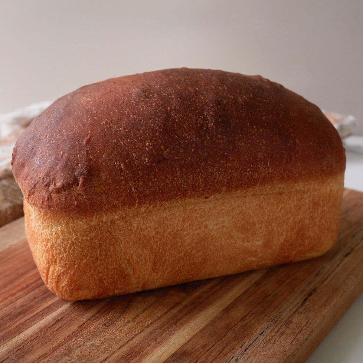 Sourdough sandwich bread baked and sitting on a wood cutting board. 