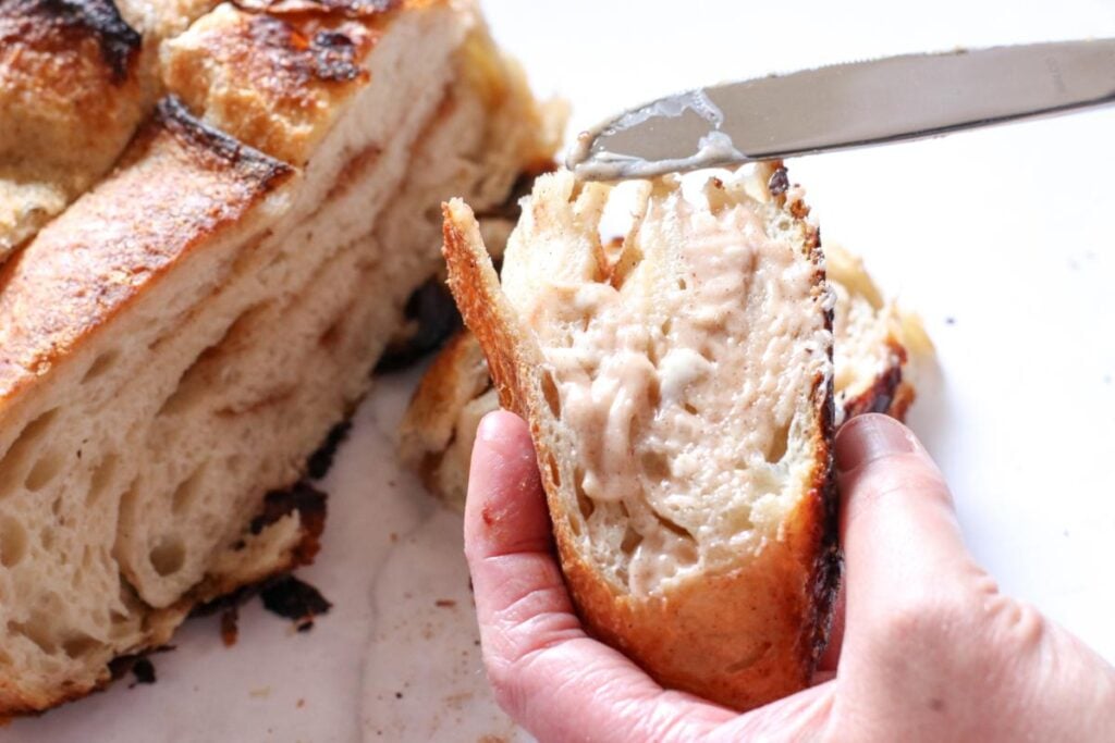 adding cinnamon honey butter with a knife on a slice of sourdough bread