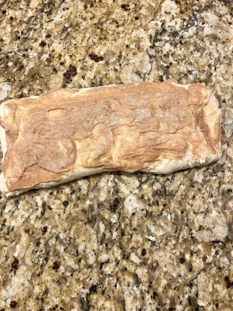 sourdough bread dough folded up with cinnamon honey butter on top