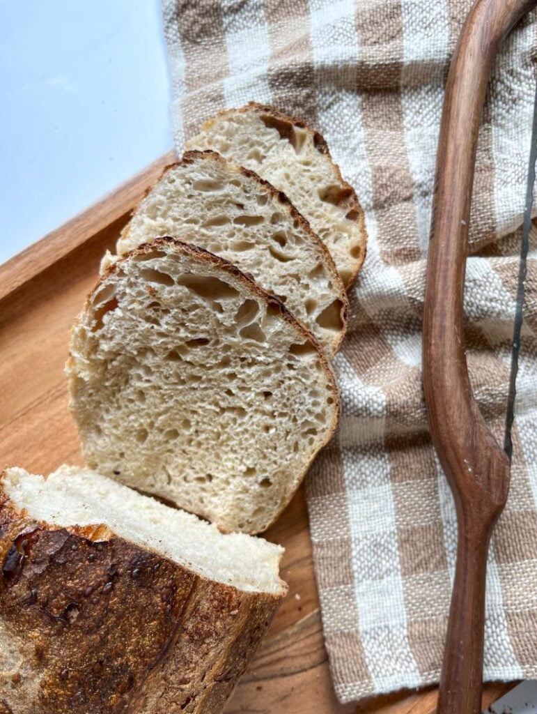 cut slices of sourdough bread in a loaf shape with a bow knife