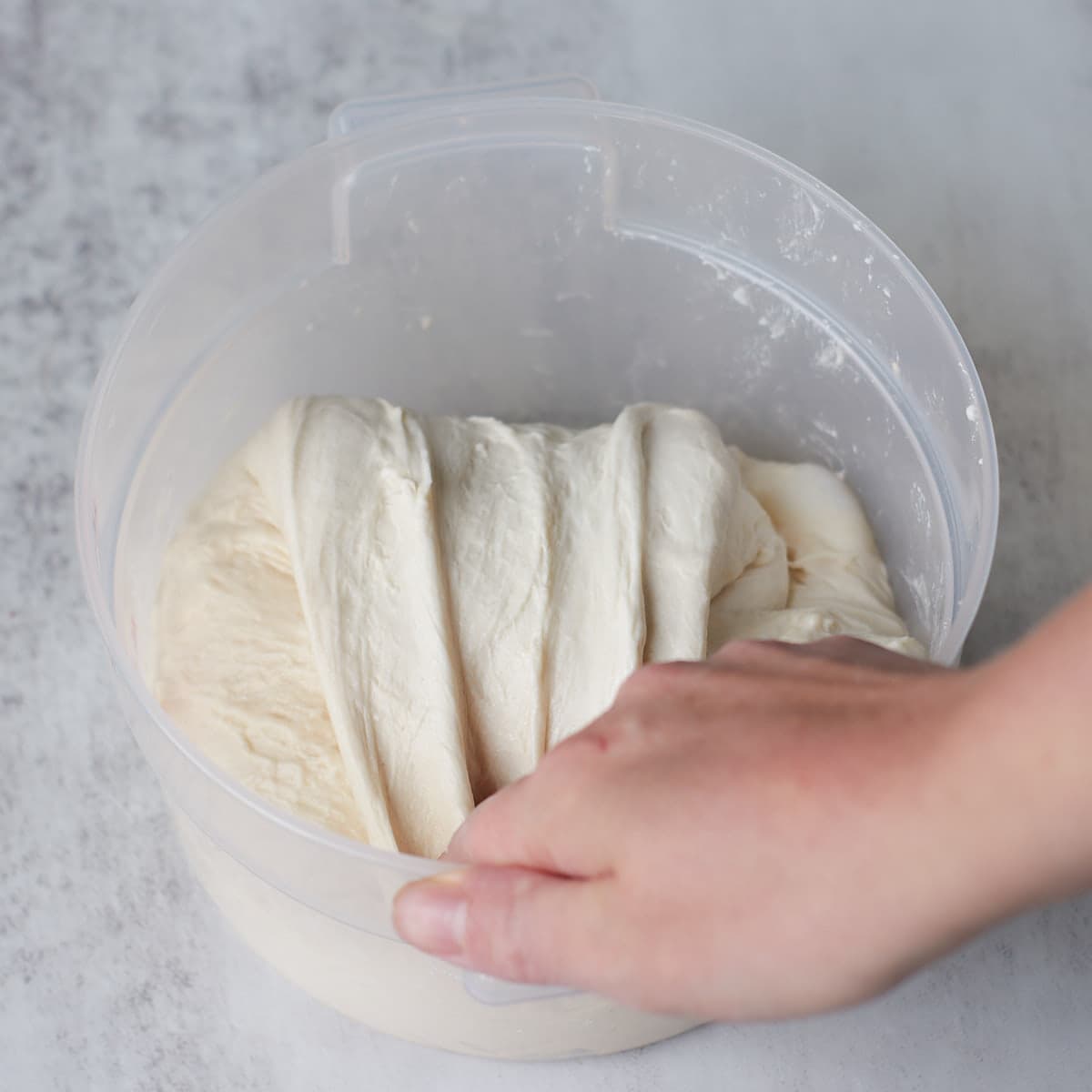 Hand performing stretch and folds on sourdough bread dough.