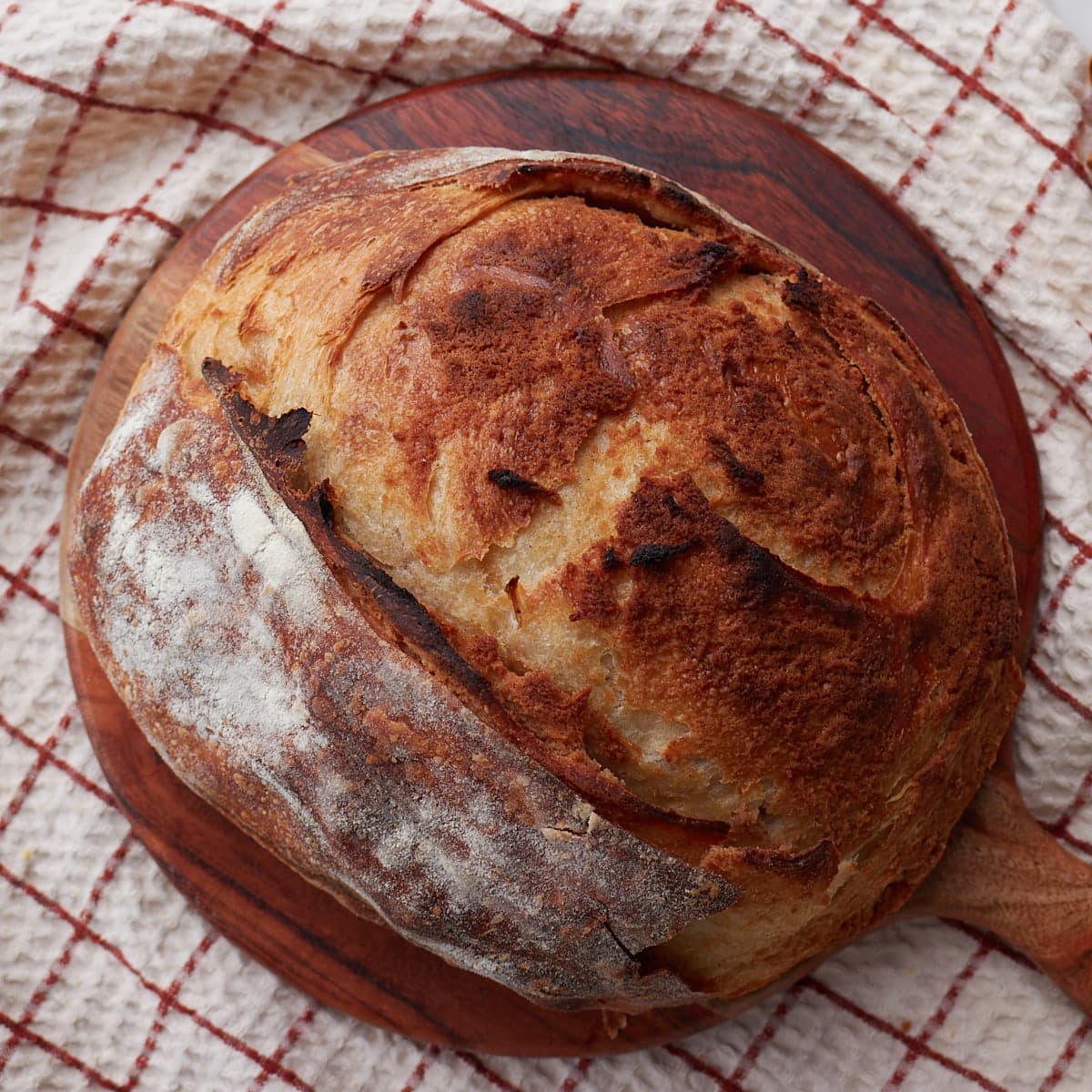Loaf of cinnamon honey butter bread on a round wooden board.