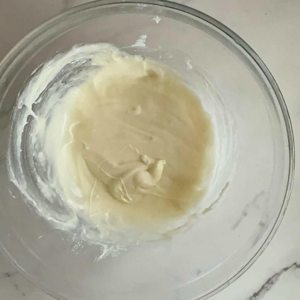 Cream cheese frosting for sourdough cinnamon rolls in a clear bowl.