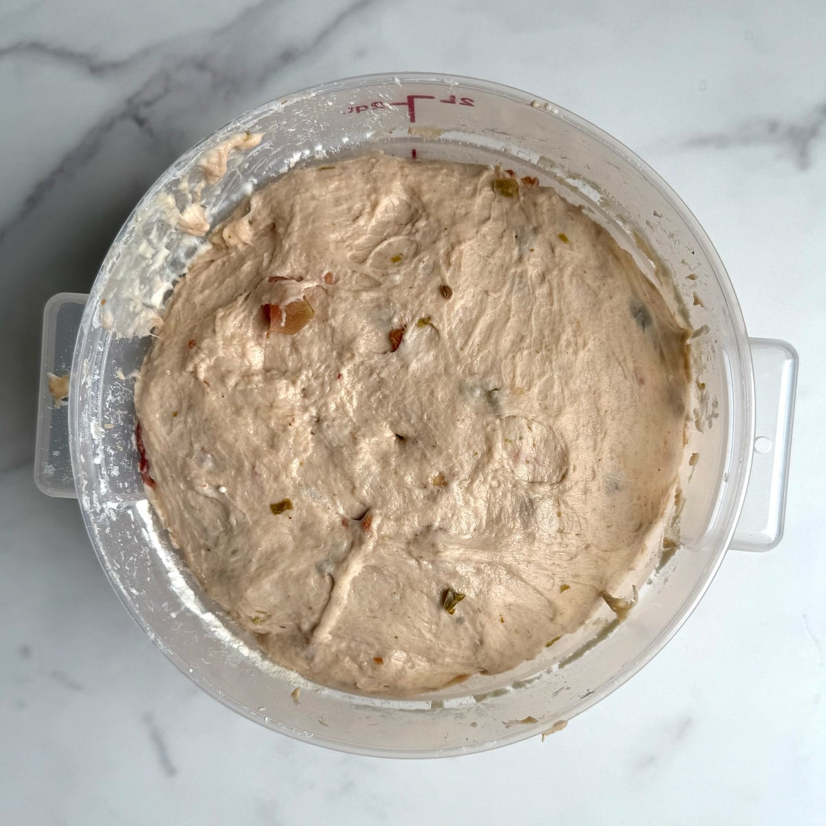 salsa focaccia dough after it has finished its first rise in a 2 quart bowl.