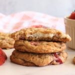 3 sourdough discard strawberry cheesecake cookies stacked on top of each other with strawberries surrounding it
