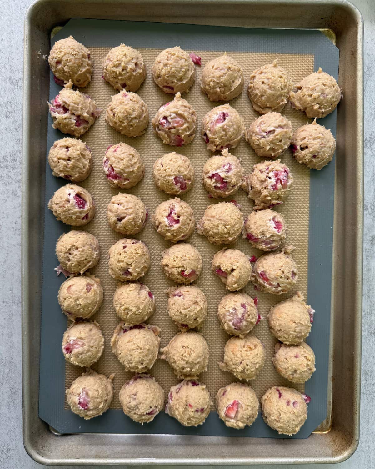 42 sourdough strawberry cheesecake cookie dough balls on a pan.