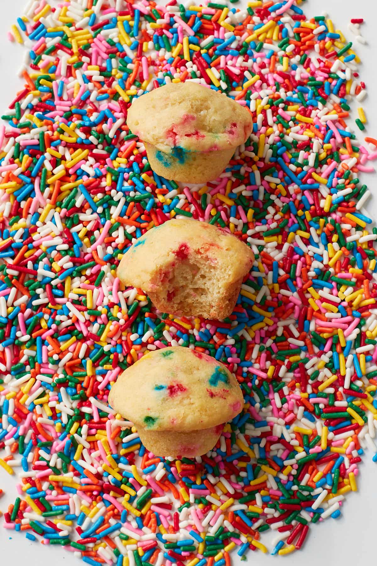 Three Sourdough Mini Muffins on top of rainbow sprinkles.