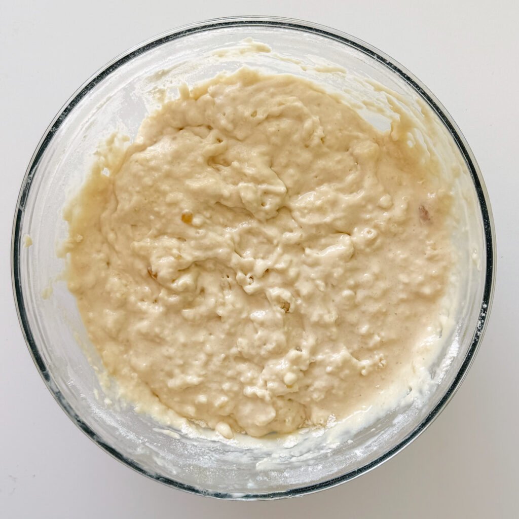 Batter for sourdough mini muffins in a clear bowl.