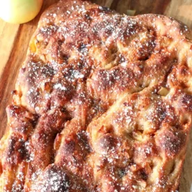 sourdough caramel apple focaccia on a wood block with apples on the top