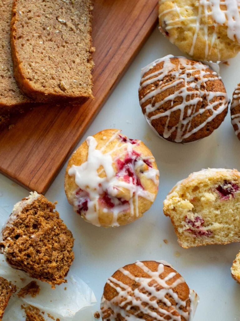 muffins scattered on a table and sliced quick bread