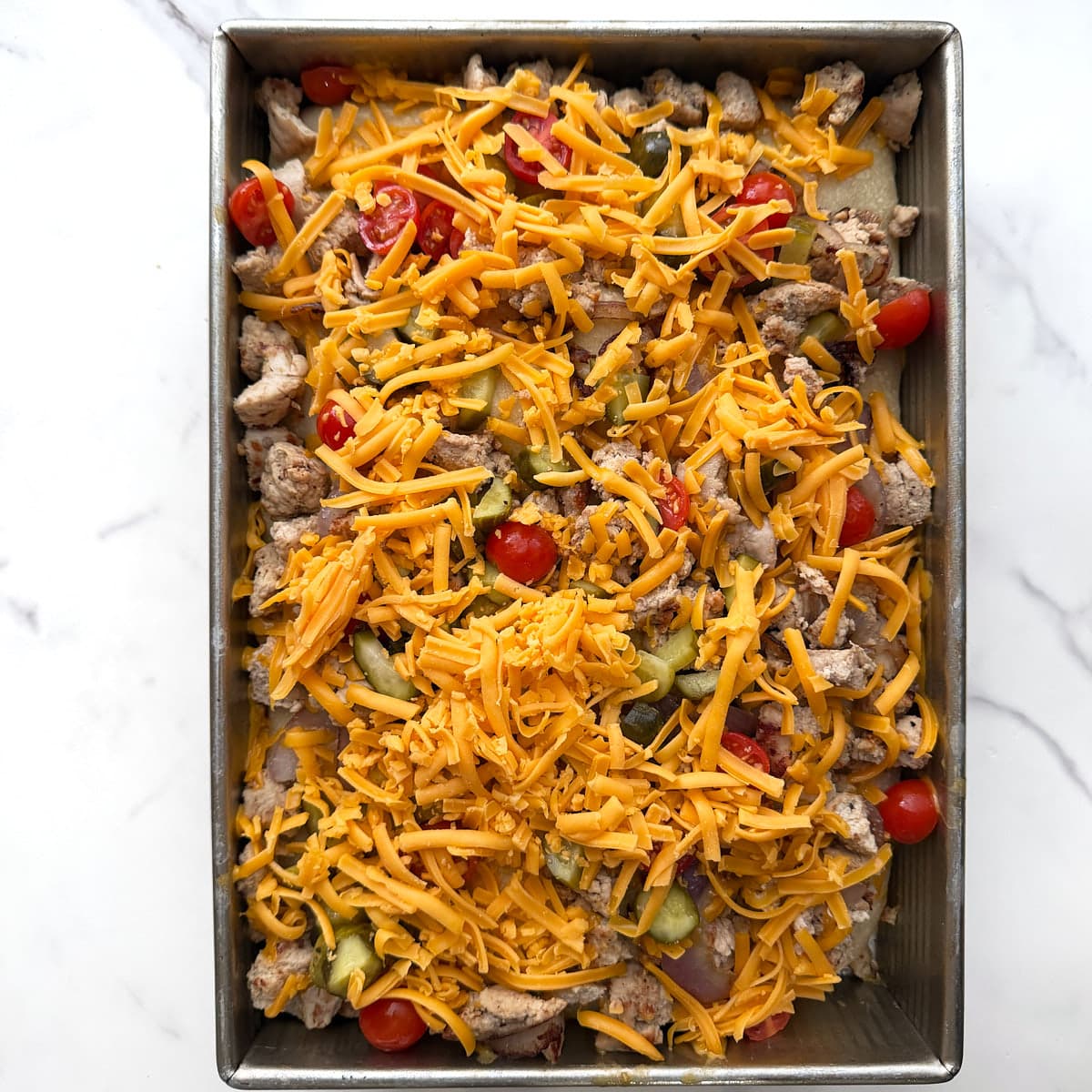 Cheeseburger toppings on a par-baked focaccia before baking. 