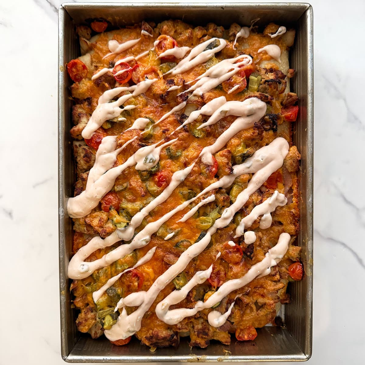 Cheeseburger sourdough focaccia topped with a drizzle of burger sauce. 