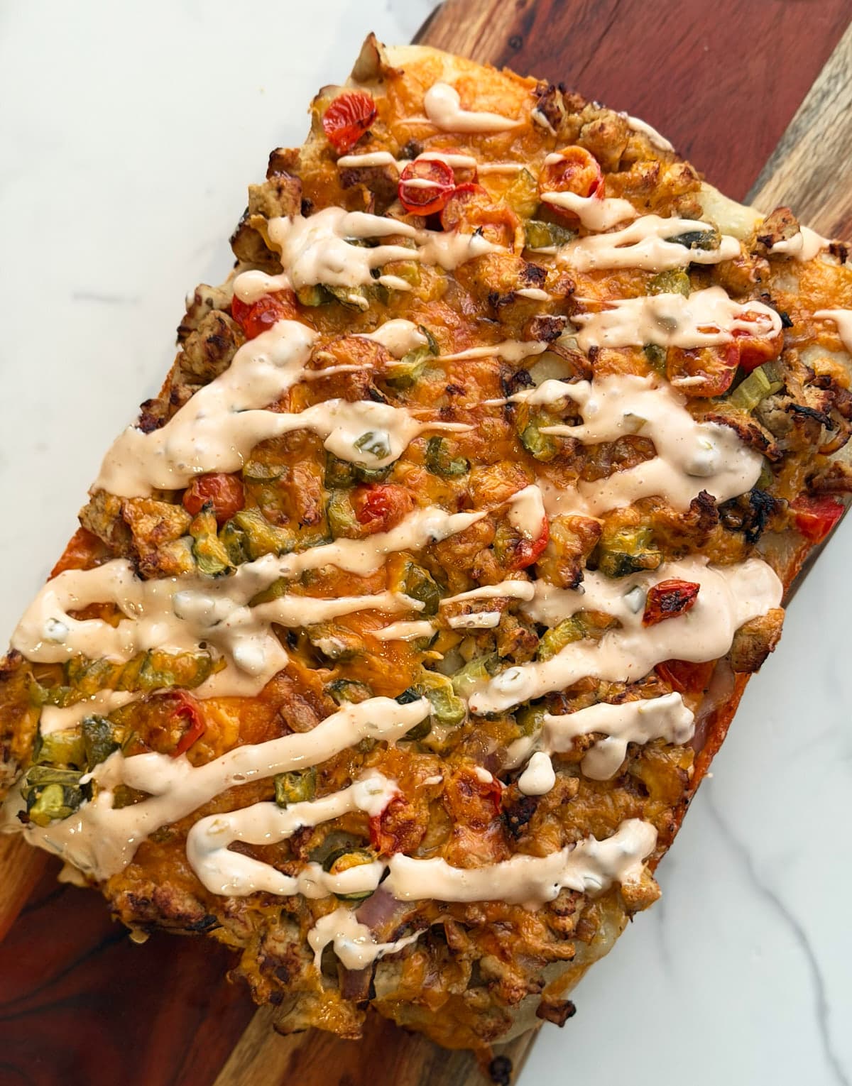 cheeseburger focaccia drizzled in sauce on a wood board. 