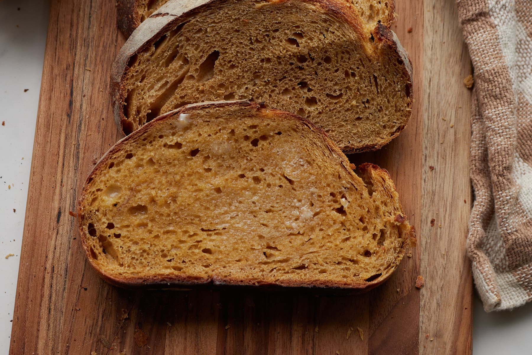 A slice of pumpkin sourdough bread with butter on top.