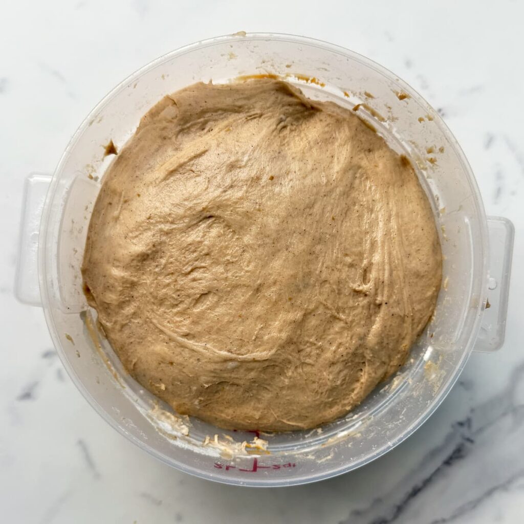 Sourdough pumpkin bread dough in a straight edge container after the first rise.