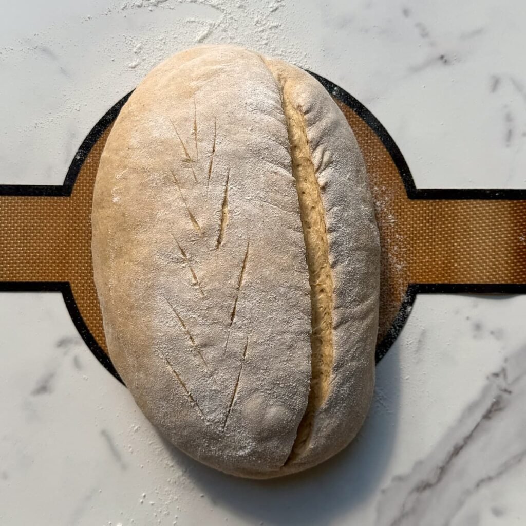 Sourdough pumpkin bread scored with a wheat stalk pattern on the left and a deeper cut on the right.