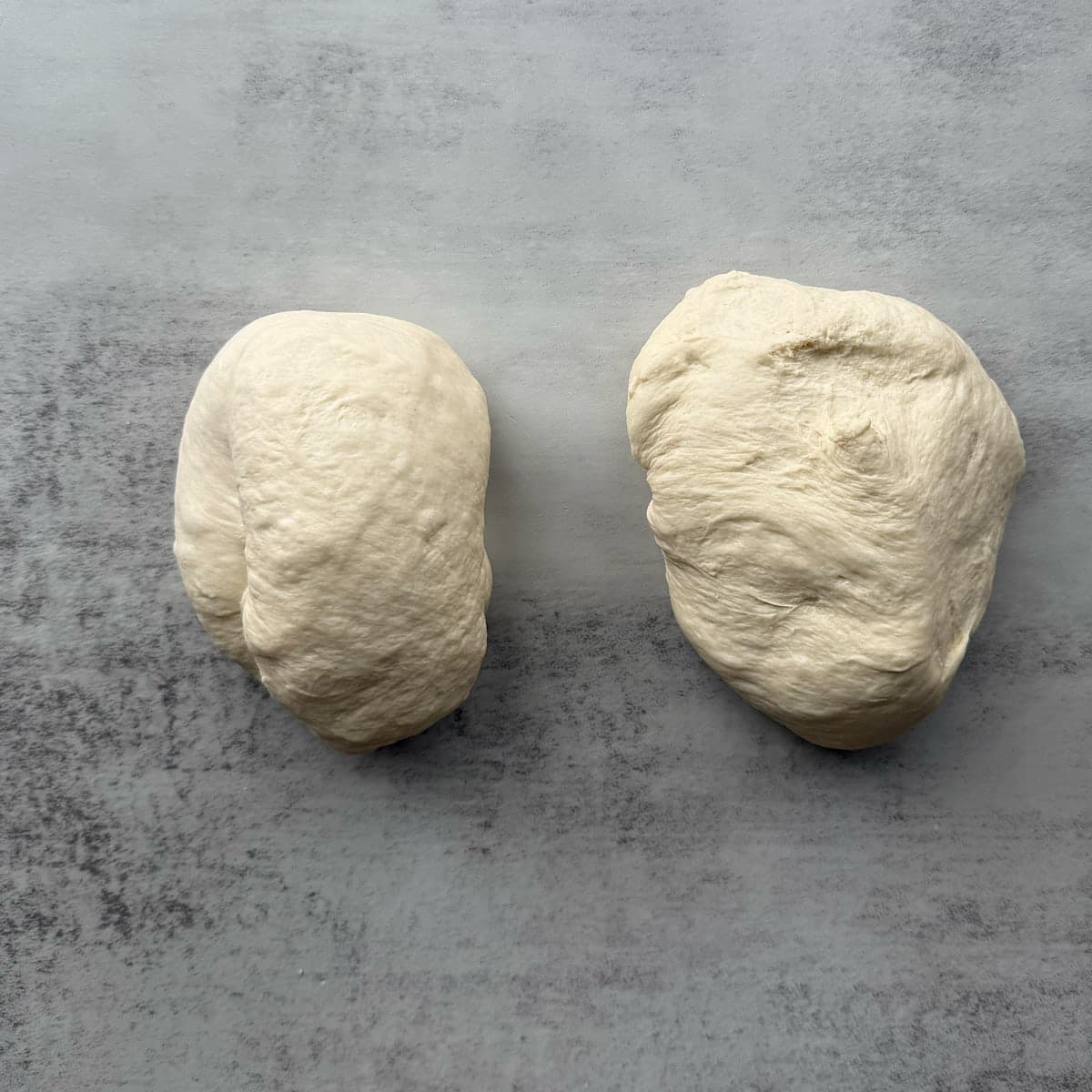 Sourdough discard french bread dough divided into two equal parts on a marble surface.