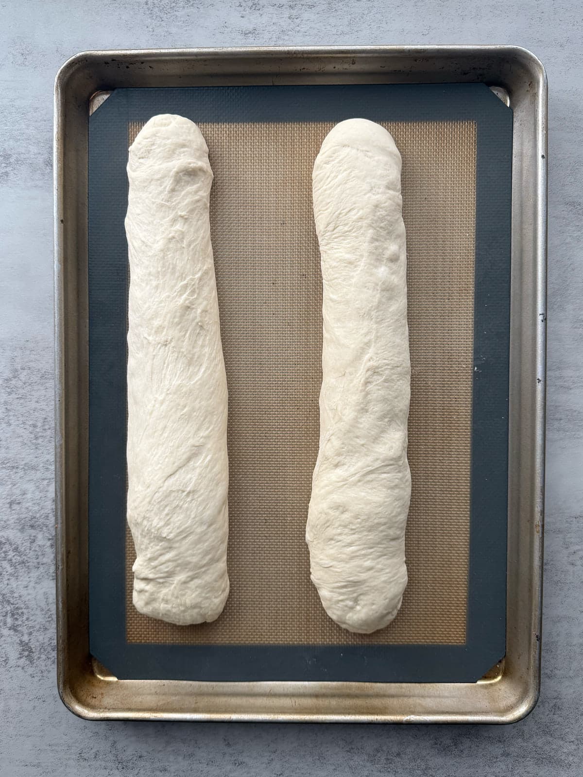 Two loaves of sourdough discard bread pre-bake arranged on a prepared baking sheet pre-rise.
