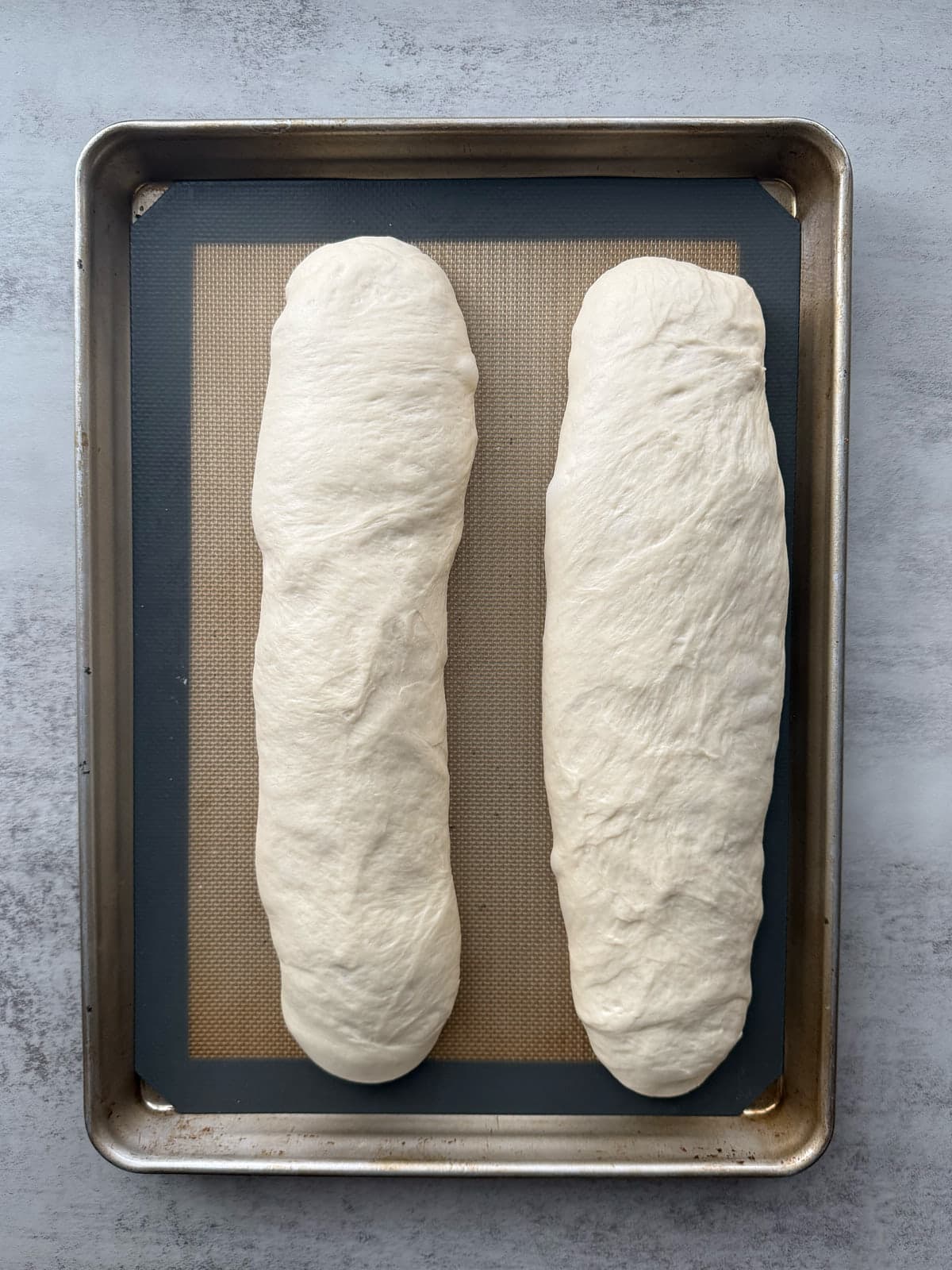 Two loaves of sourdough discard bread pre-bake arranged on a prepared baking sheet post-rise.