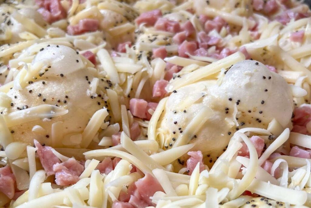 dimpled focaccia dough with ham and swiss cheese on top