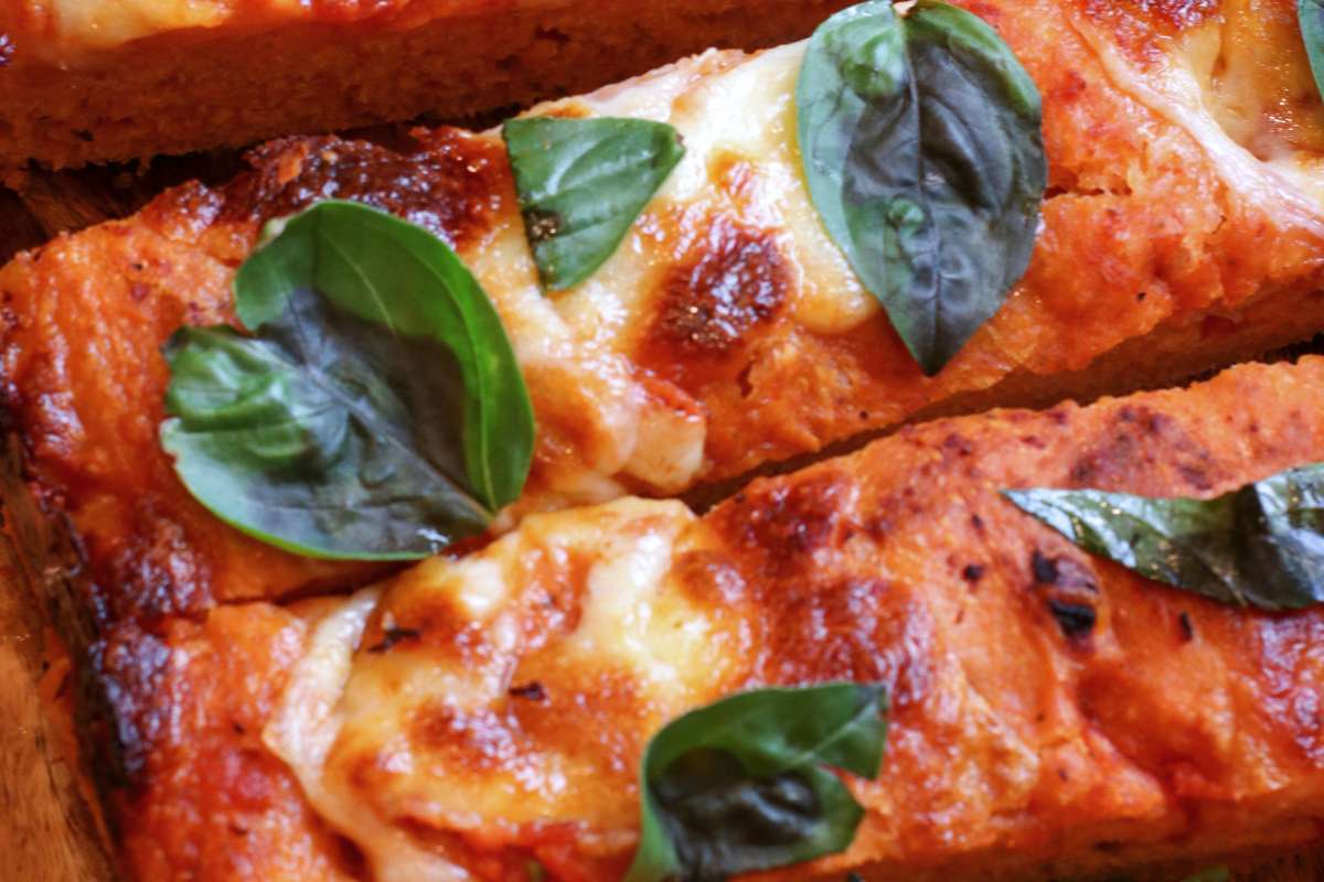 sourdough focaccia topped with mozzarella cheese, marinara sauce, and basil leaves on top