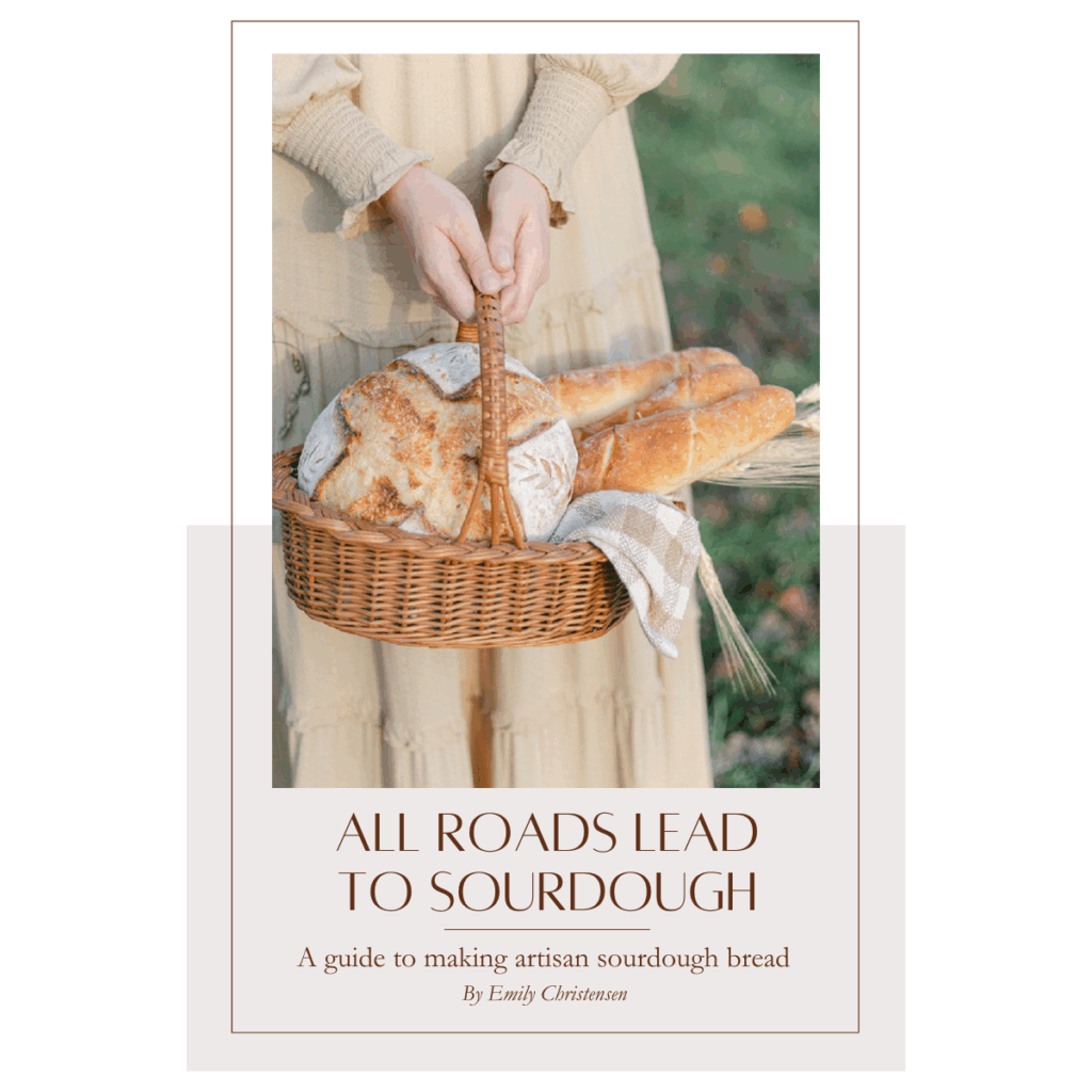 All roads lead to sourdough ebook cover with a woman in a beige dress holding a basket of sourdough bread. 