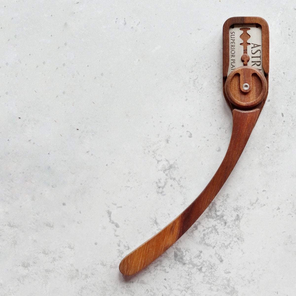 A wooden bread lame with a gooseneck on a countertop. 