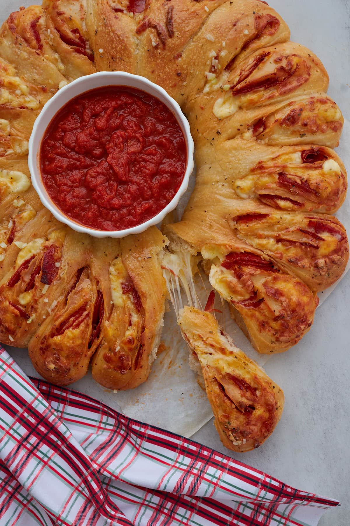 Sourdough Pizza Wreath with a small bowl of marinara sauce in the center with a piece pulled off.