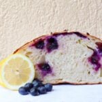 Inside view of Lemon Blueberry Sourdough Bread next to fresh blueberries and a lemon slice.