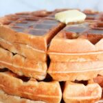 Close-up of Protein Sourdough Waffles with a pat of butter and maple syrup on top.