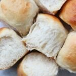 Sourdough dinner rolls next to each other on top of a white background.