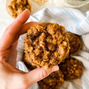 hand holding Sourdough Bran Muffins over a basket filled with muffins.