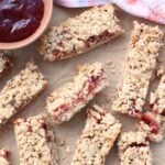 oatmeal sourdough breakfast bars with a layer of jam next to a small bowl of raspberry jam