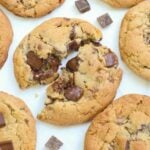 Sourdough Chocolate Chip Cookie cut in half with gooey chocolate on a white background.