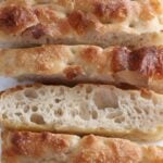 Slices of sourdough focaccia on a white background.