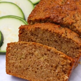 Slices of Sourdough Zucchini Bread next to fresh slices of zucchini.