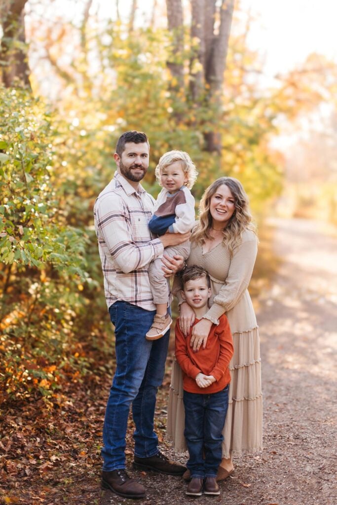 2 boys and a mom and dad in front of a tree in the forest