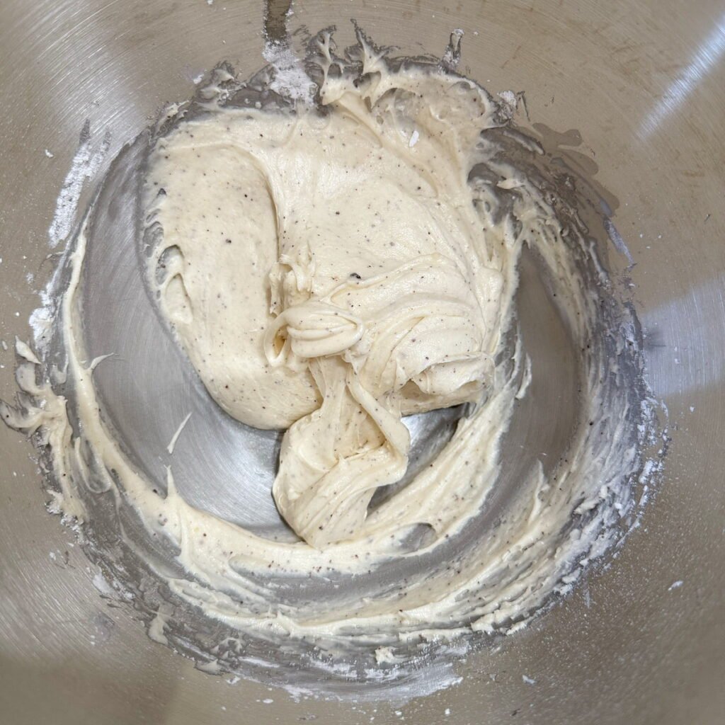 Brown butter cream cheese frosting inside of the metal bowl of a stand mixer.