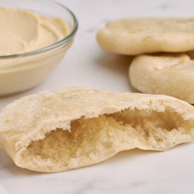 half a pita bread with a pocket in the middle next to a small bowl of hummus