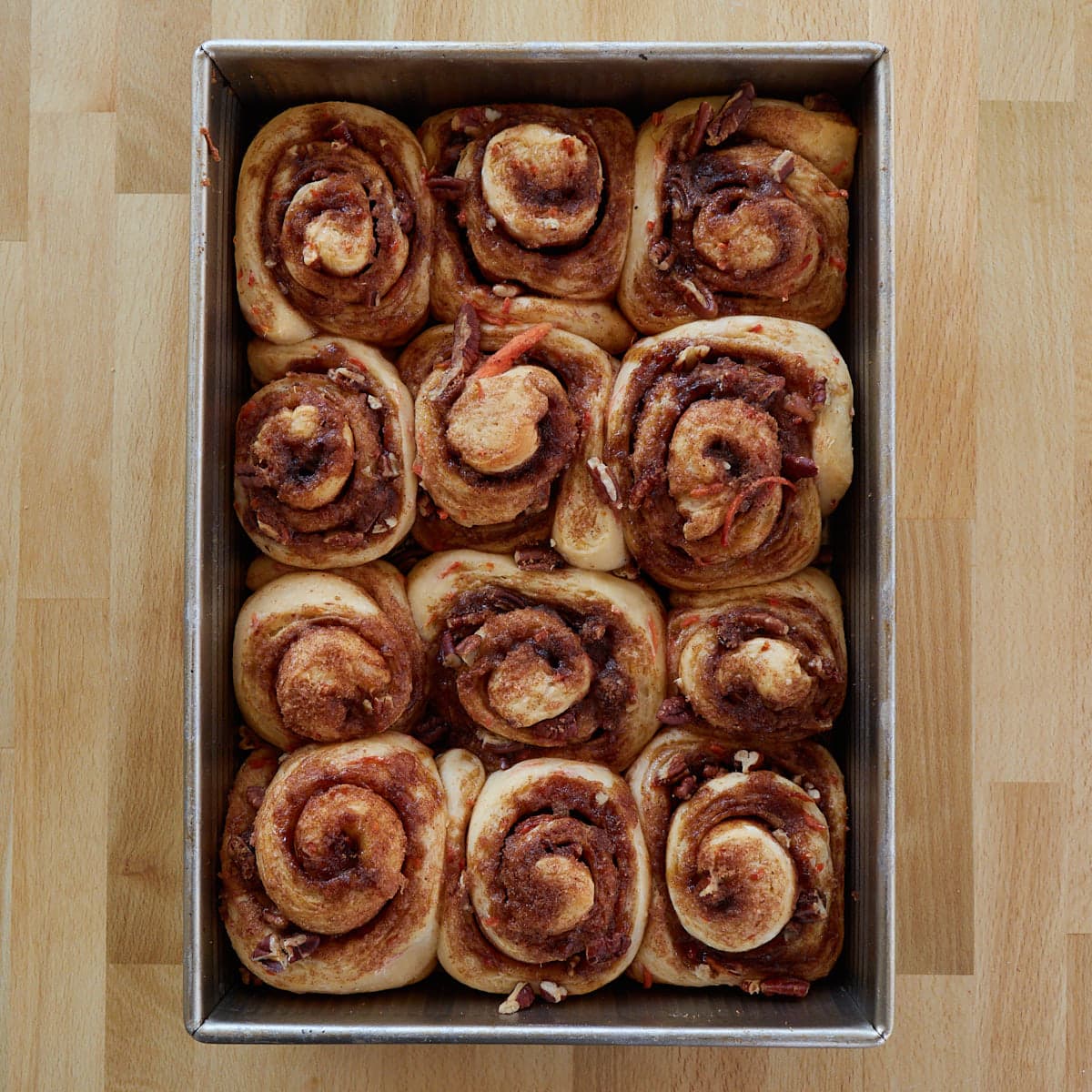 12 baked carrot cake sourdough cinnamon rolls in a 9x13 inch pan after the second rise.