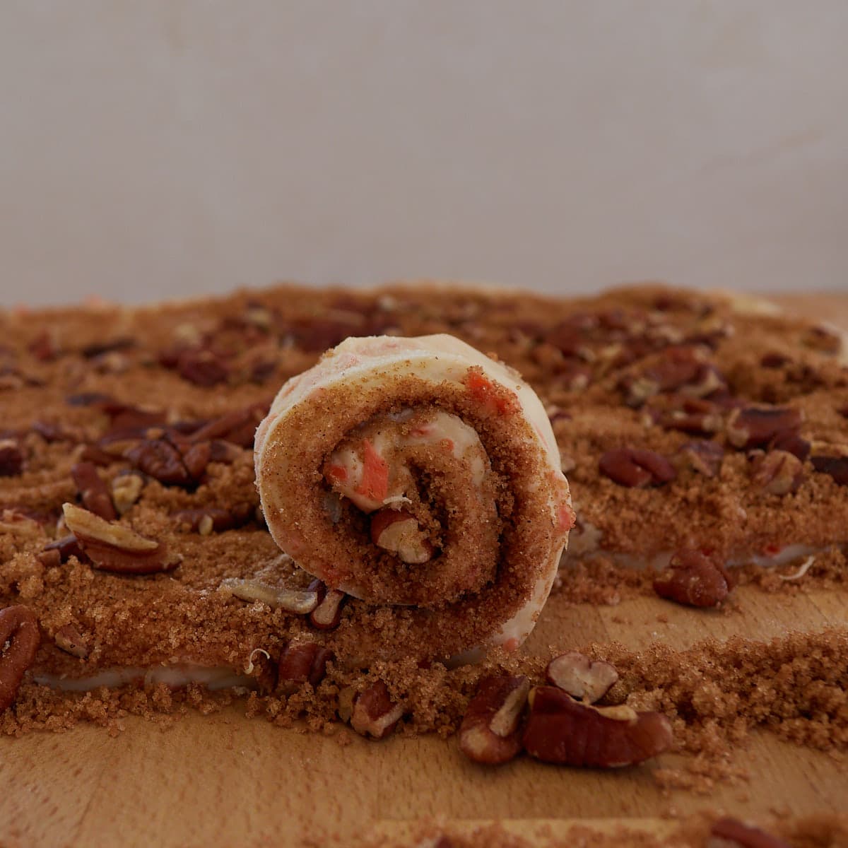 A slice of the cinnamon roll dough is being rolled up. 