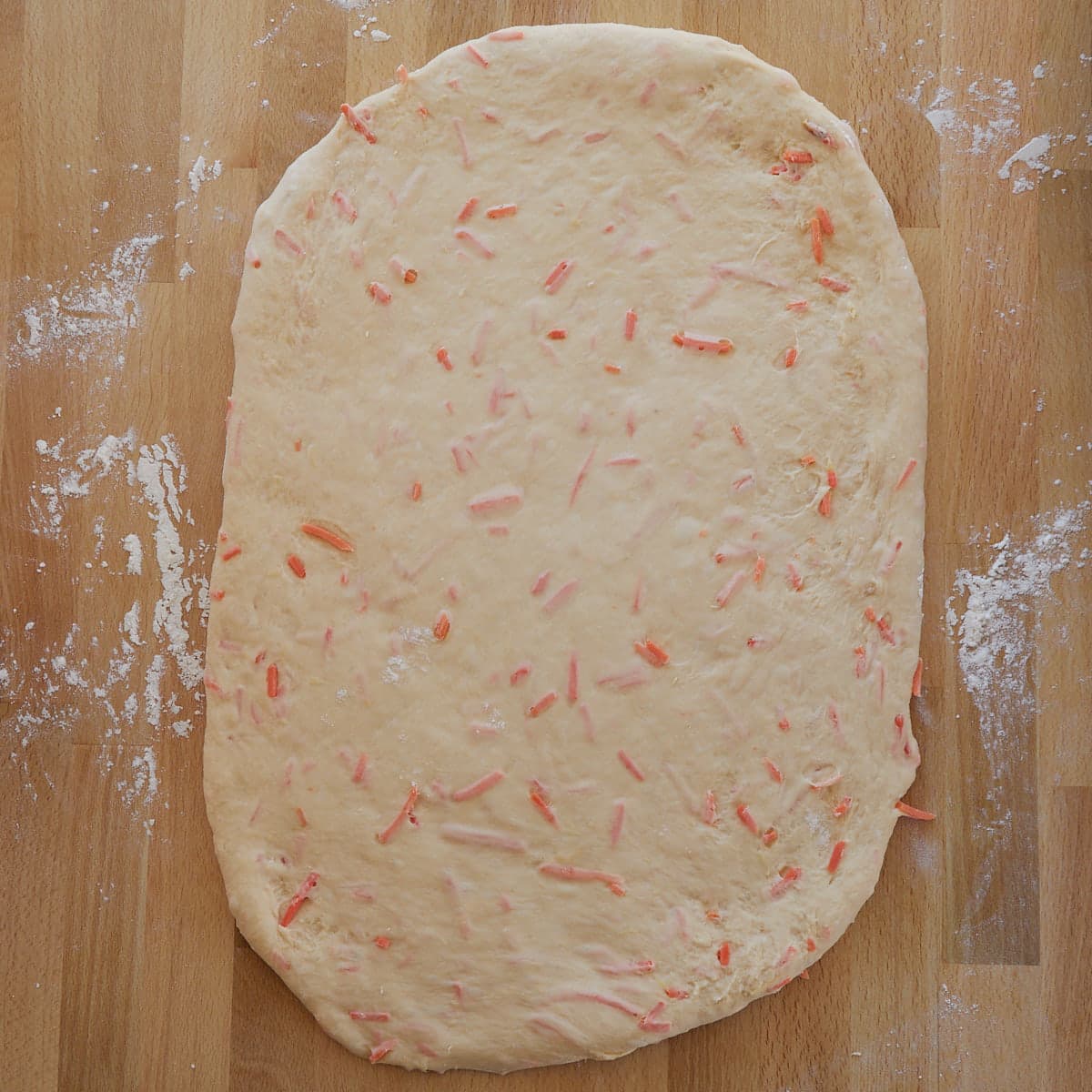 Carrot cake cinnamon roll dough rolled out on a wood board. 